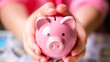 A person is holding a pink piggy bank