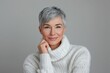 © photolas - Elderly beautiful woman with gray short cut hair. Old model in white knitted sweater poses on light gray background.