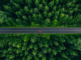 Fototapeta Na ścianę - Aerial view of car with a roof rack on a country road and green woods in Finland