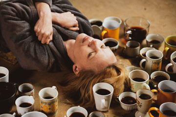 Wall Mural - Woman surrounded by many cups of coffee, deadline concept. Workaholism, overtime, the need to be alert. Tired woman.