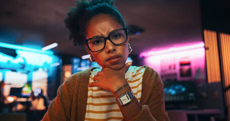 Aufkleber - Stylish Young Black Woman Looking at Camera With Confusion While Working on Desktop Computer in Creative Office. Female Developer Trying to Fix a Bug, Unsure of the Source of the Issue
