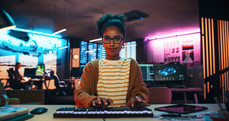Aufkleber - Portrait of a Black Female Developer Writing Code in a Creative Office with Neon Lights. Young Woman Focused on Typing on Keyboard and Working on Desktop Computer. Point of View of Screen Monitor 