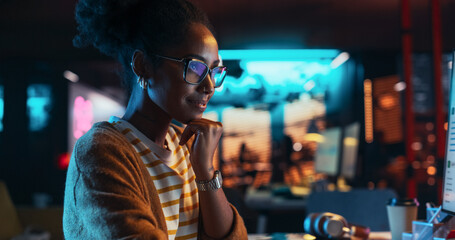 Poster - Female Talented Digital Marketing Specialist Working on Computer at Office in the Evening. Young Black Businesswoman in Creative Agency, Smiling and Researching Business Analytical Data