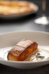 Grilled salmon steak served with two creamy sauces on a plate in a restaurant