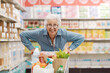 © StockPhotoPro - Cheerful funny senior woman pushing a full shopping cart