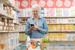 © StockPhotoPro - Happy senior woman buying groceries and using a smartphone
