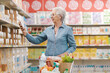 © StockPhotoPro - Senior woman checking supermarket products using her smartphone