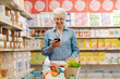 © StockPhotoPro - Happy senior woman buying groceries and using a smartphone