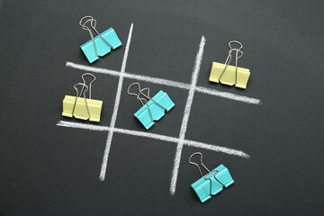 Wall Mural - Tic tac toe game made with paper clips on chalkboard, top view