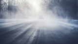 Fototapeta  - fog on a dangerous winter slippery road, a car with headlights in a risky climate cold and ice