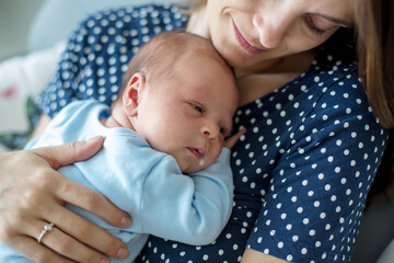 Wall Mural - Young mother, holding tenderly her newborn baby boy