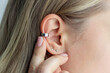 Cuff earring. Cropped shot of a young blonde woman showing silver earring with finger. Jewelry, accessories