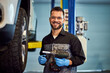 © bnenin - Portrait of a smiling mechanic working at his garage, holding a drill.