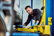 © bnenin - A focused mechanic man finding the right place to put a crane for the car.
