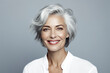 A woman with a short gray hair and a white shirt is smiling. She is wearing red lipstick