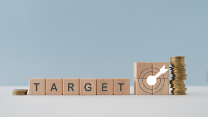 TARGET and dartboard icon on wooden cube blocks with stack of coin for marketing, business target, saving, investment concept