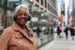 Middle aged or senior black woman portrait against city street blurred background, photo of happy smiling active African American elderly lady with large headphones, AI generative