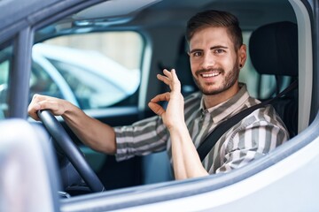 Poster - Hispanic man with beard driving car doing ok sign with fingers, smiling friendly gesturing excellent symbol