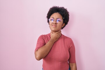 Poster - Beautiful african woman with curly hair standing over pink background touching painful neck, sore throat for flu, clod and infection