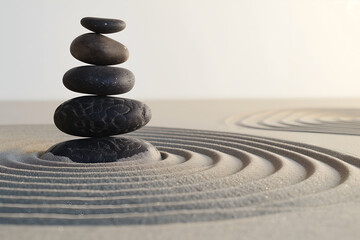 Wall Mural - A pile of smooth stones are stacked on top of each other in the center, surrounded by raked sand with circular patterns