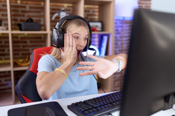 Poster - Young caucasian woman playing video games wearing headphones looking at the watch time worried, afraid of getting late