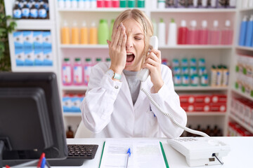 Sticker - Young caucasian woman working at pharmacy drugstore speaking on the telephone yawning tired covering half face, eye and mouth with hand. face hurts in pain.