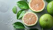 Juicy pomelo cut in half with fresh leaves on wet background. Refreshing pomelo slices with water droplets for culinary use. Vibrant halved pomelos with natural moisture on a grey backdrop.