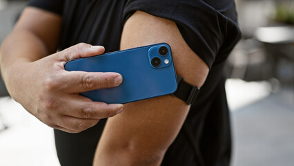 Canvas Print - Confident young latin man harnessing technology, scanning his diabetes sensor with smartphone on city street, monitoring glucose levels with a smile