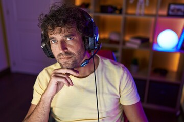 Canvas Print - Young hispanic man streamer sitting on table with serious expression at gaming room