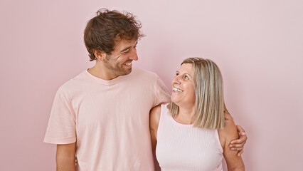 Wall Mural - Mother and son sharing a confident, joy-filled hug, smiling together over an isolated pink background, radiating love and happiness