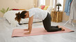 © Krakenimages.com - Middle-aged hispanic woman practicing yoga in her well-lit bedroom, adding tranquility to the room's cozy decor.