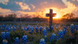 Cross in rural field filled with bluebonnets at sunrise for easter background.