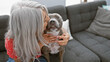 © Krakenimages.com - Heartwarming moment, grey-haired middle age woman shares a loving kiss with her dog, sitting together on home sofa