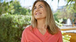 © Krakenimages.com - A smiling mature caucasian woman in a pink sweater enjoys nature in an outdoor park setting.