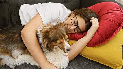 Canvas Print - A young hispanic woman lovingly cuddles with her dog on a colorful couch, enjoying a peaceful moment indoors.