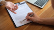 © wattana - Cropped shot of insurance agent showing place for signature on paper contract document to client.