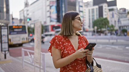 Sticker - Beautiful hispanic woman with glasses in tokyo, digital connection via smartphone on city streets