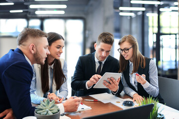 Sticker - Young handsome man gesturing and discussing something while his coworkers listening to him sitting at the office table