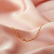A delicate gold chain bracelet placed against a subtle blush pink background