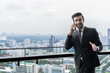 © Jack Tamrong - Handsome Indian businessman  using smartphone in high building balcony in downtown city