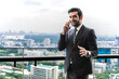 © Jack Tamrong - Handsome Indian businessman  using smartphone in high building balcony in downtown city