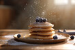 Tasty pancakes on a plate with powdered sugar and blueberries on a wooden table with beautiful sunlight from the window in the background with space for text or inscriptions

