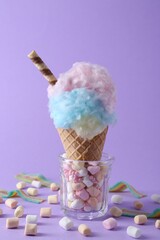 Wall Mural - Sweet cotton candy in waffle cone and marshmallows on purple background