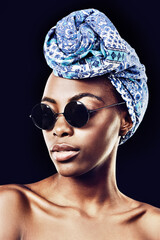 Wall Mural - Face, fashion and culture with African model in studio isolated on black background for heritage. Aesthetic, woman and sunglasses with confident young person in trendy headwear for traditional style