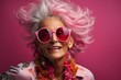 Elderly woman with exuberant pink hair and oversized pink-framed sunglasses exudes joy and style against a vibrant pink background