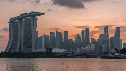 Wall Mural - Downtown skyline of Singapore as viewed from across the water from The Garden East day to night timelapse. Singapore.