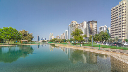 Wall Mural - Corniche boulevard beach park along the coastline in Abu Dhabi timelapse hyperlapse with skyscrapers on background.