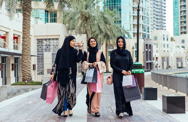 Wall Mural - Three women friends going out in Dubai. Girls wearing the united arab emirates traditional abaya