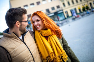 Wall Mural - Smiling couple enjoying on vacation, young tourist having fun walking and exploring city street during the day.