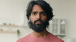 © Yuliia - Close up head shot Arabian muslim guy stand in kitchen room. Portrait Indian ethnic bearded man serious looking at camera calm businessman alone homeowner holder renter house unhappy face look at home